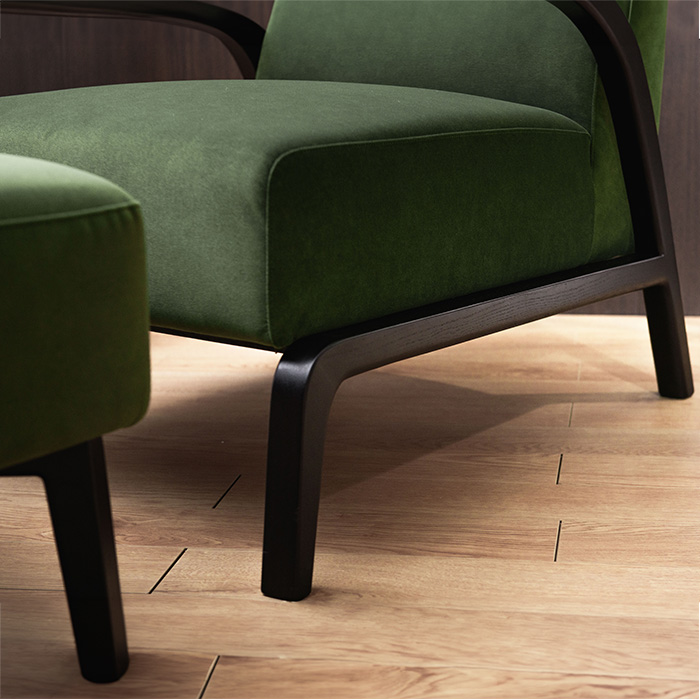 Moderne groen fluwelen fauteuil met armleuning en poef