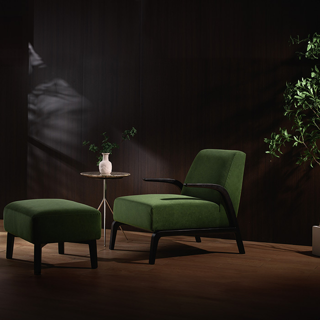 Moderne groen fluwelen fauteuil met armleuning en poef